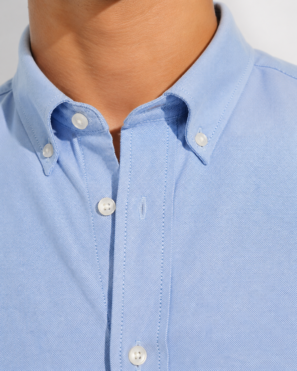 Close up of the button-down collar and Oxford weave on Cauzeway chambray blue shirt.