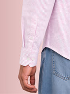 Close up texture of the breathable puckered 100% cotton seersucker weave and angled sleeve cuff on a Cauzeway pink striped shirt.