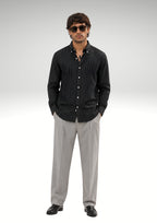 Model wearing Cauzeway black pinstripe shirt engineered for the Indian body type, styled casually and untucked with grey trousers.